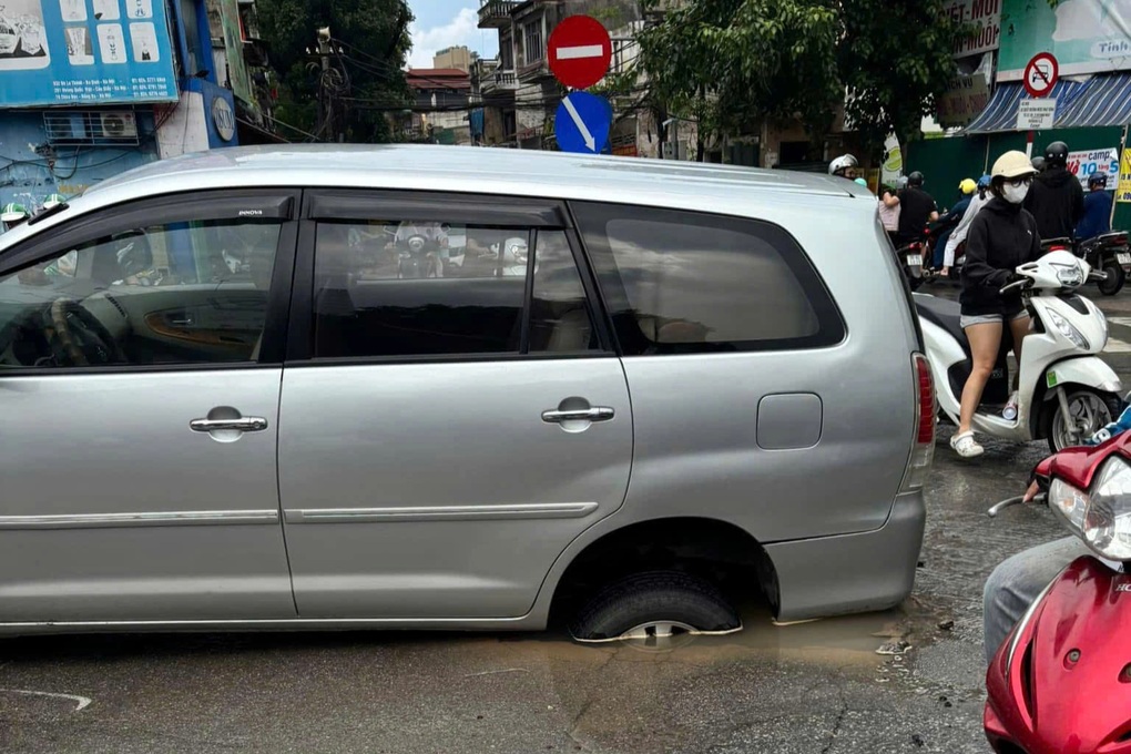 Hà Nội: Ô tô đang đi trên đường bất ngờ bị tụt bánh xuống hố - 1